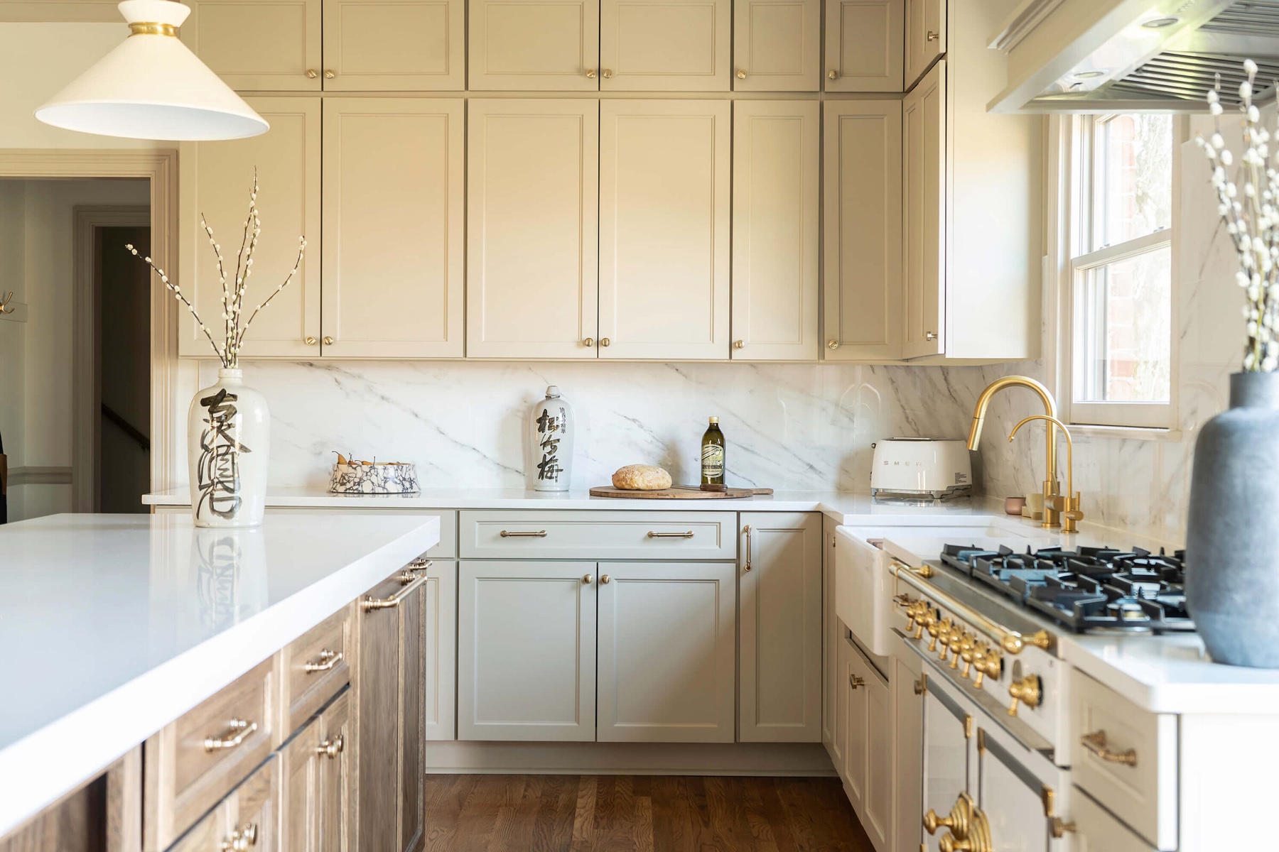 Cream cabinetry with marble backsplash and brass hardware
