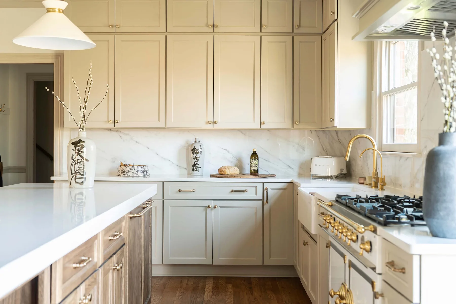 Cream cabinetry with marble backsplash and brass hardware